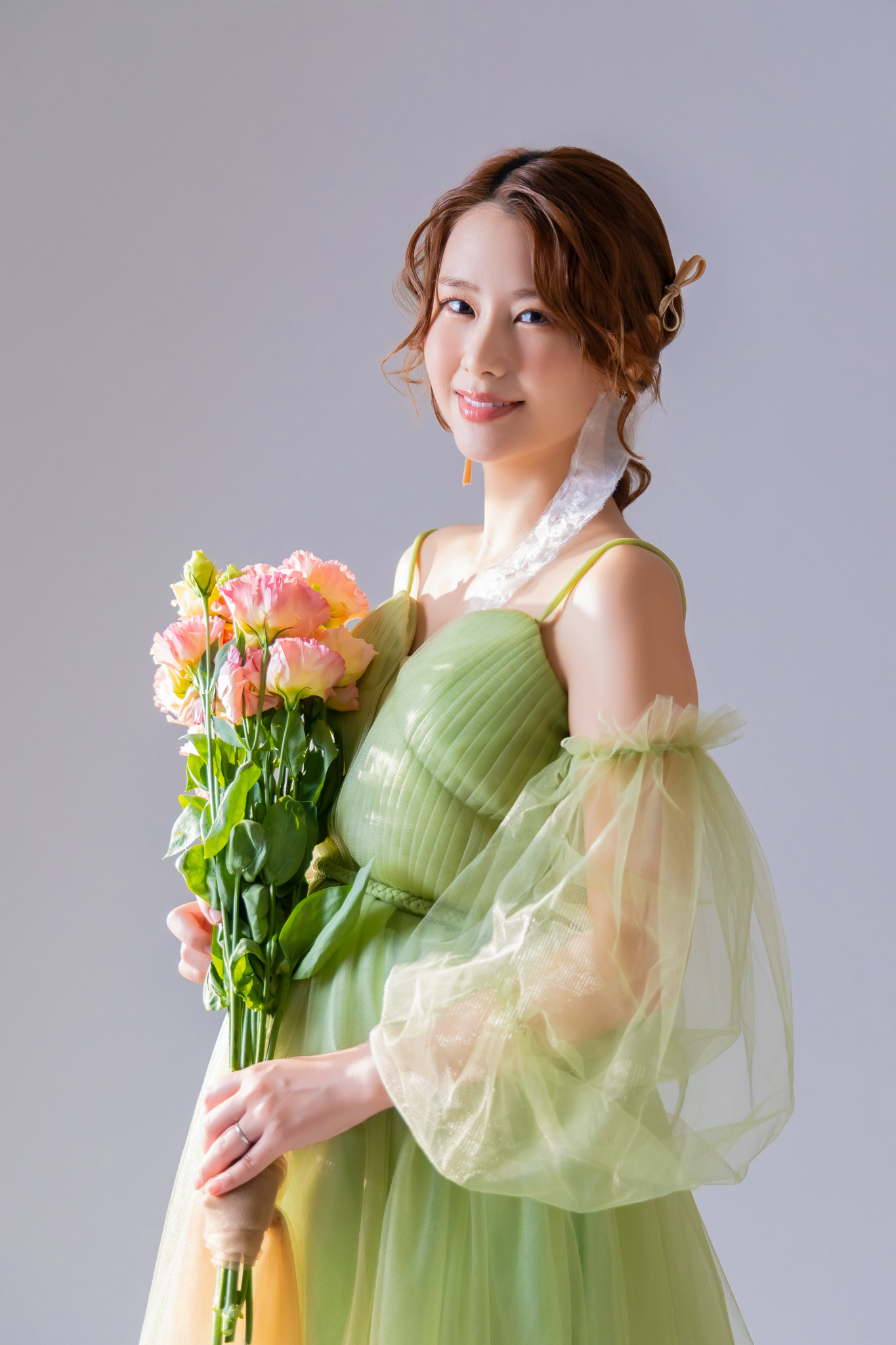 グリーンのドレスに合わせた花束を抱える妊婦