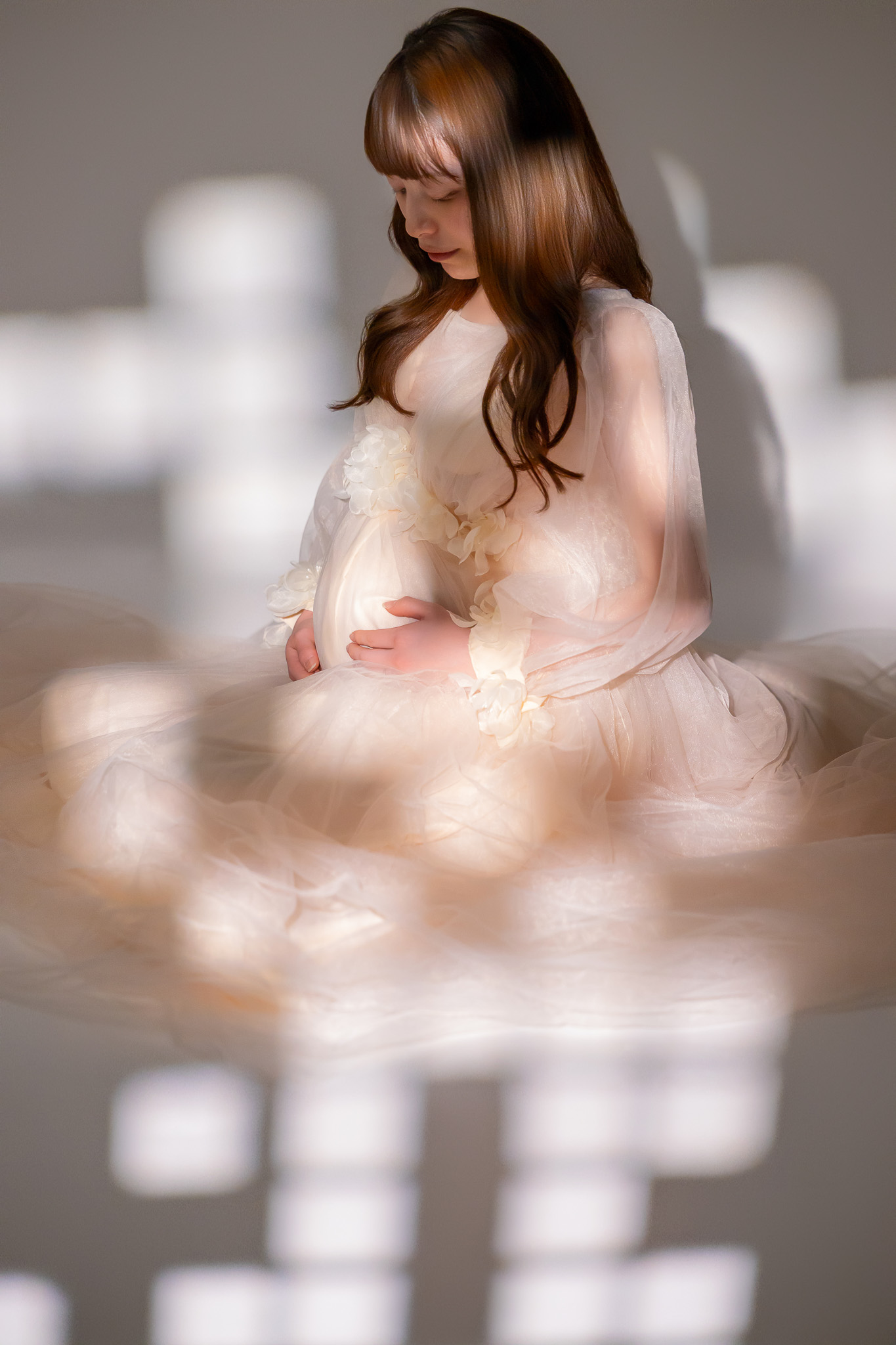 やわらかな光の中、ドレスをまとってお腹に手を添える姿