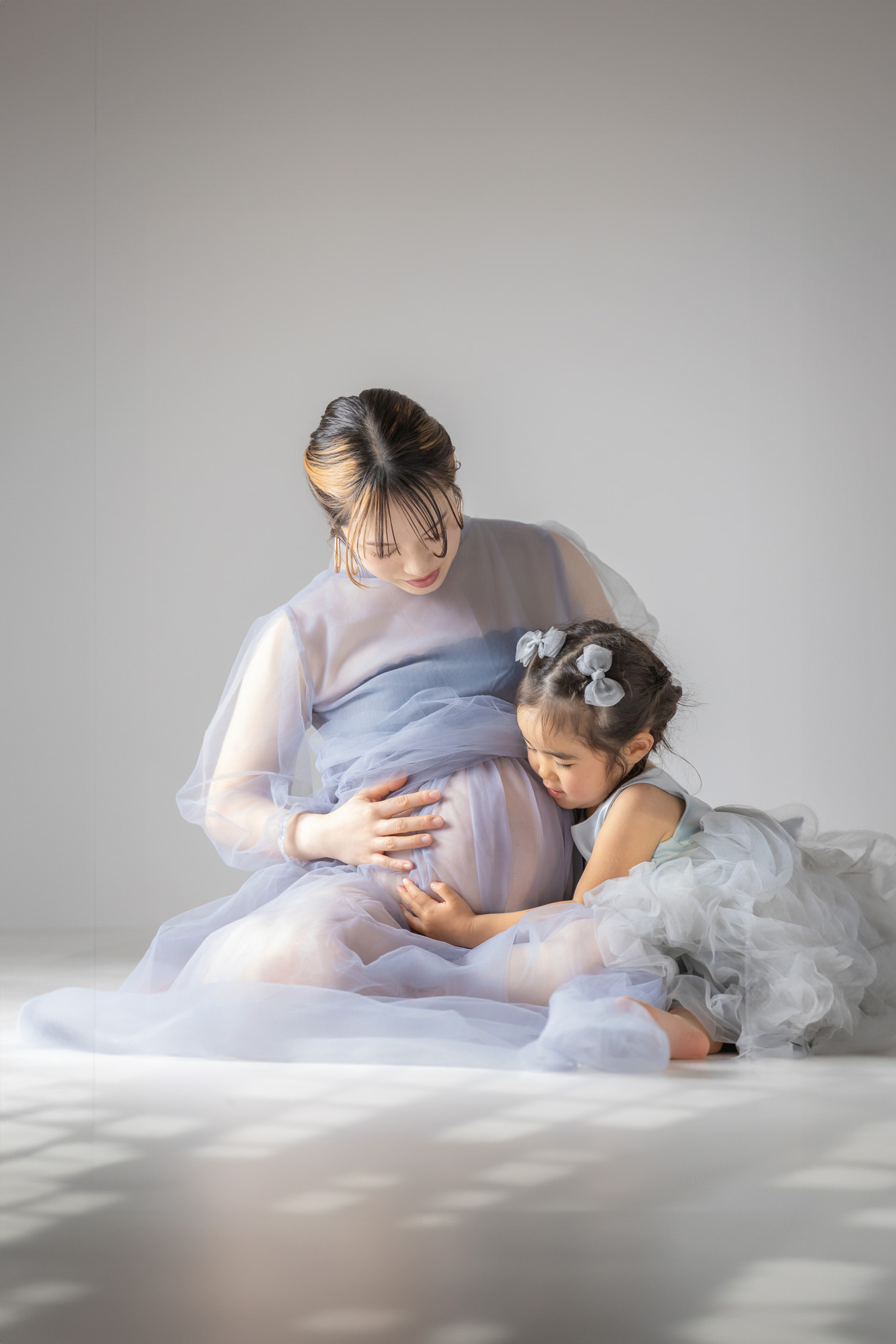 母のお腹に手を当て、そっと寄り添う上の子