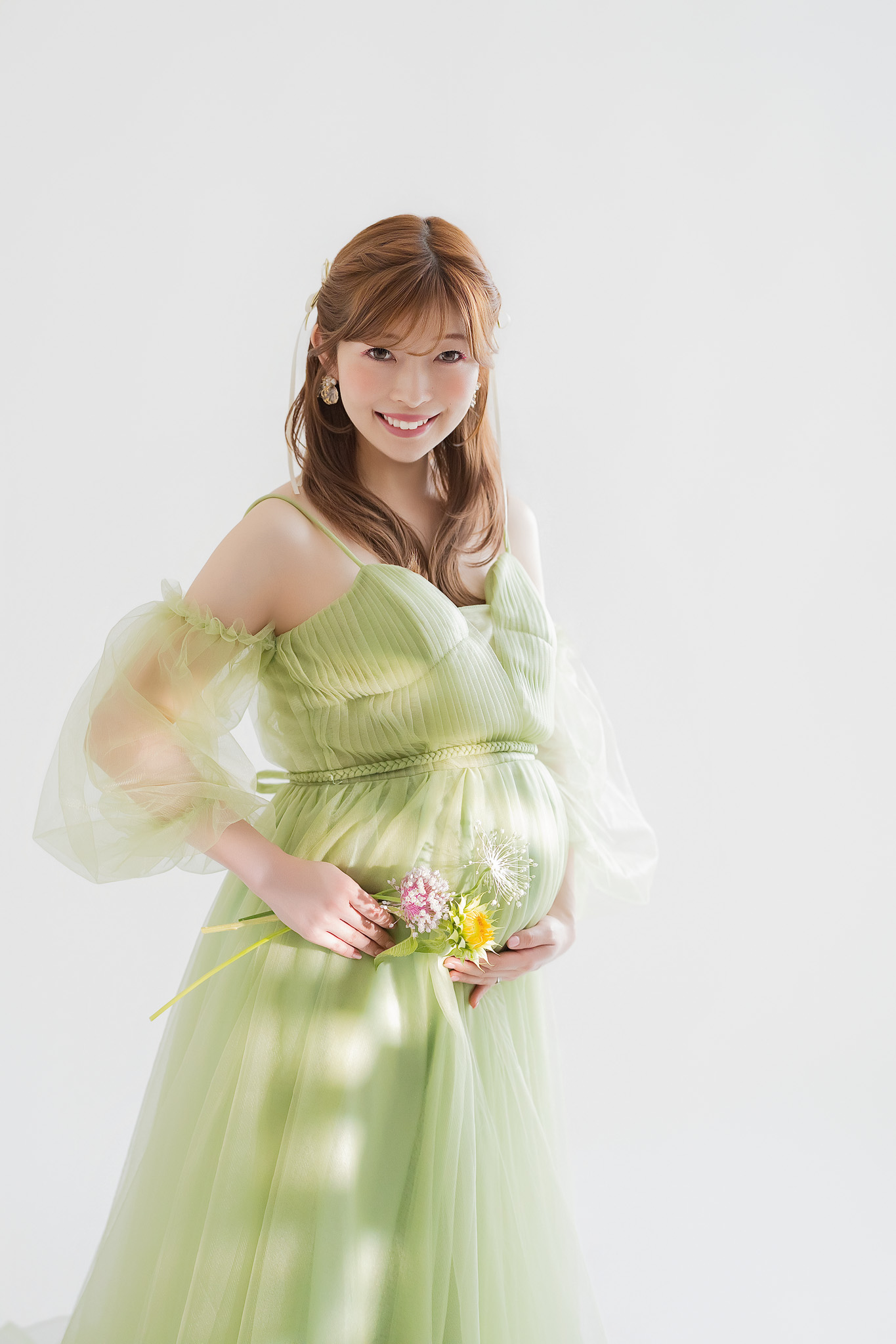 毛先をゆるく巻いて下ろした髪と、グリーンのチュールドレス