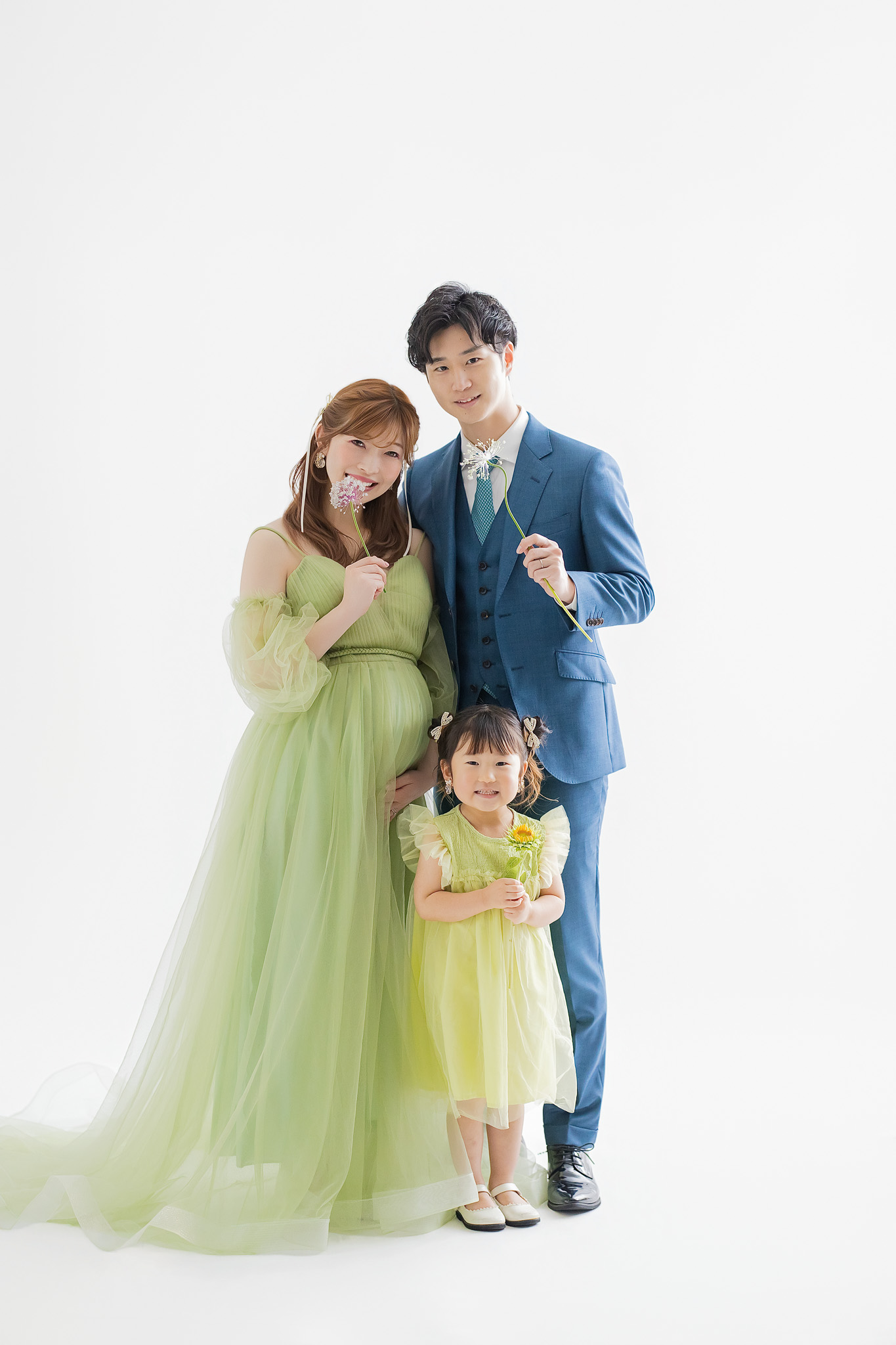 白い背景の前に並ぶ、ご夫婦と上の子の家族写真
