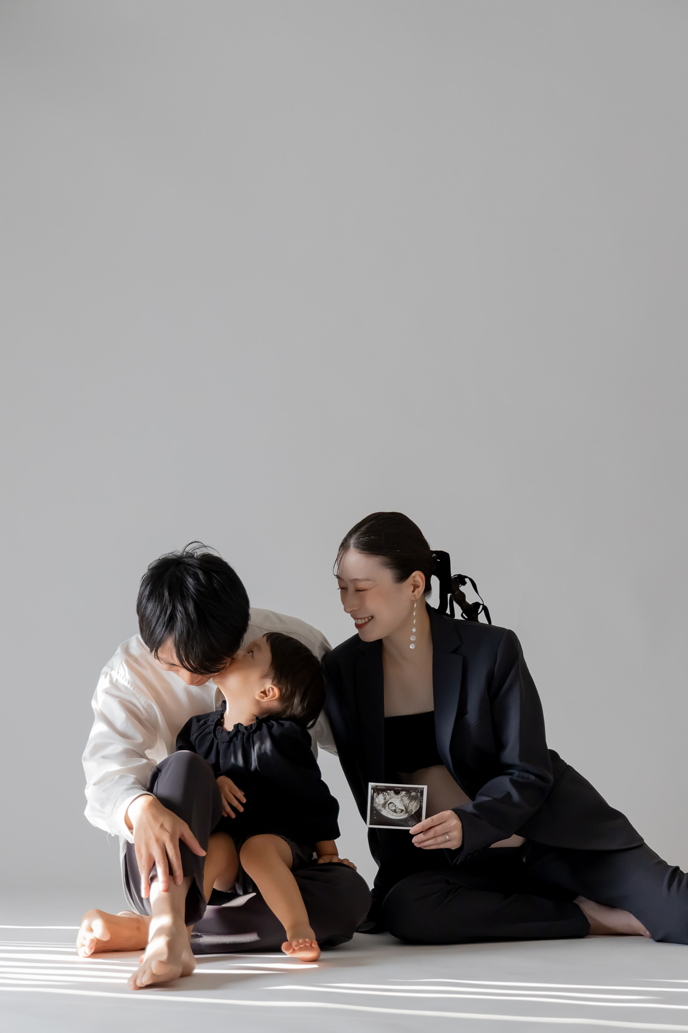 床に座り、上の子とエコー写真を囲むご家族