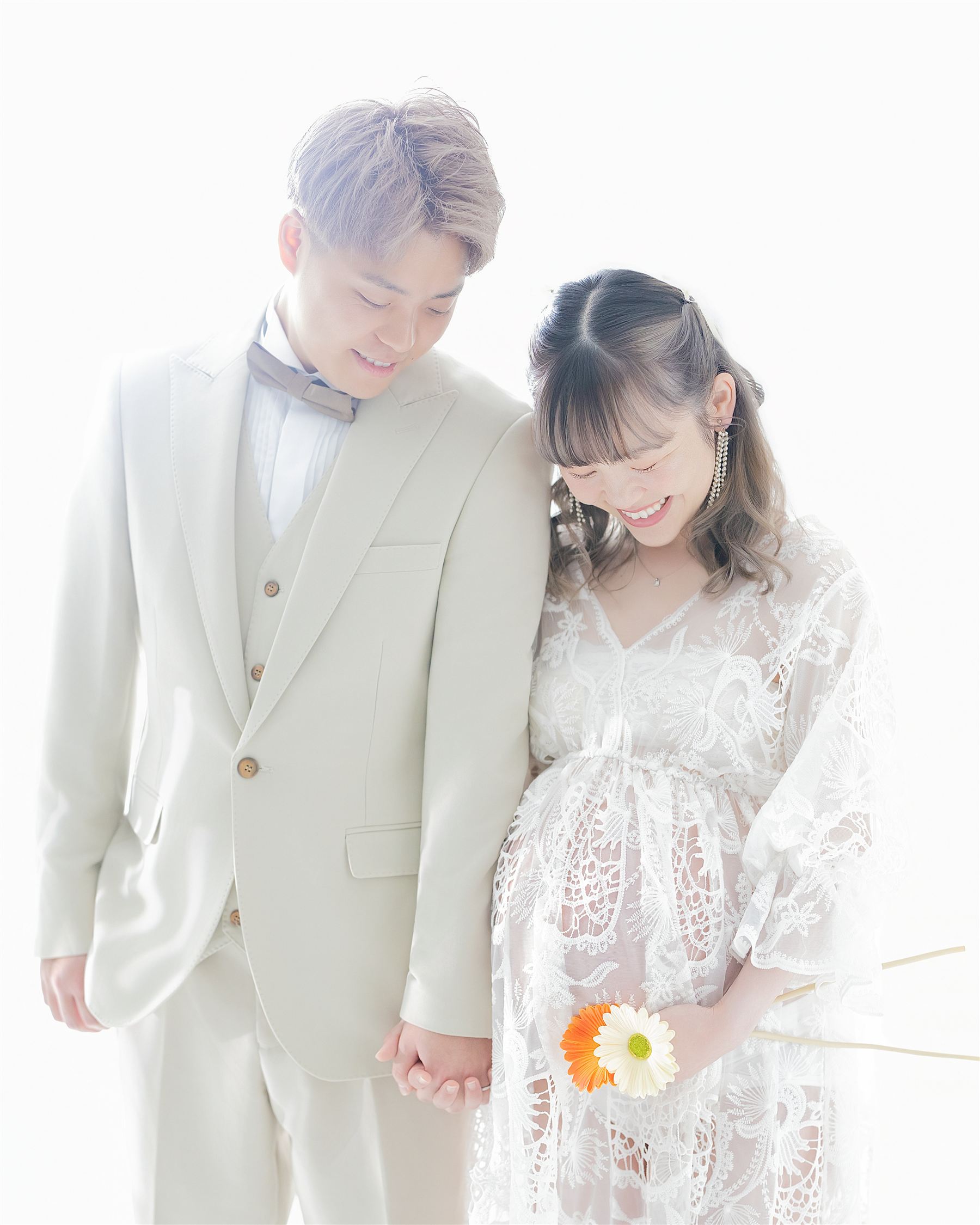 手をつなぎ寄り添うご夫婦。花を手にした妊婦の優しい笑顔