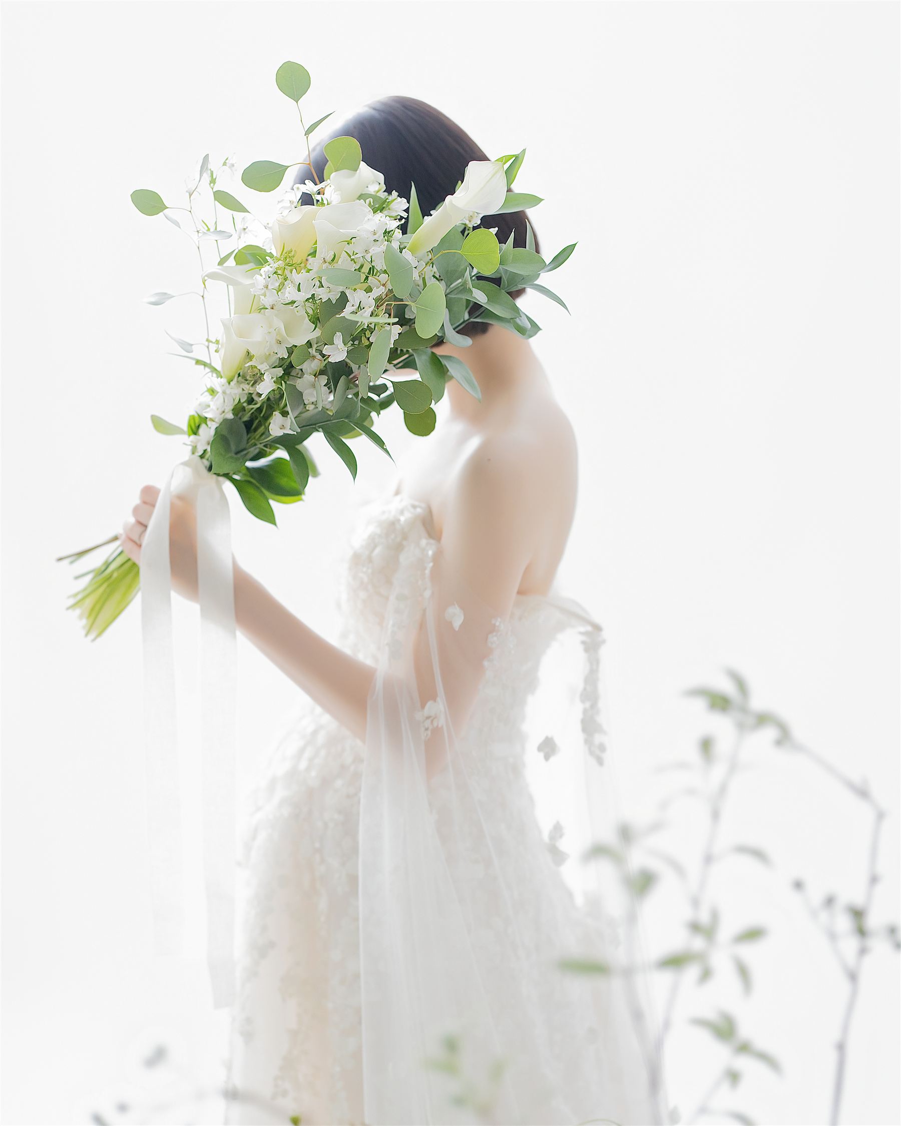白い花束を手に、ドレスをまとう妊婦の後ろ姿