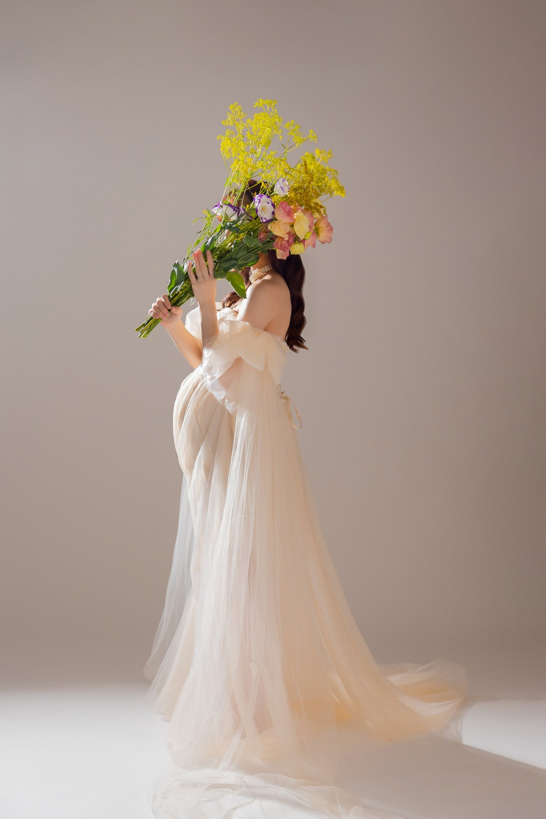 花束を高く掲げた、シフォンドレスの立ち姿