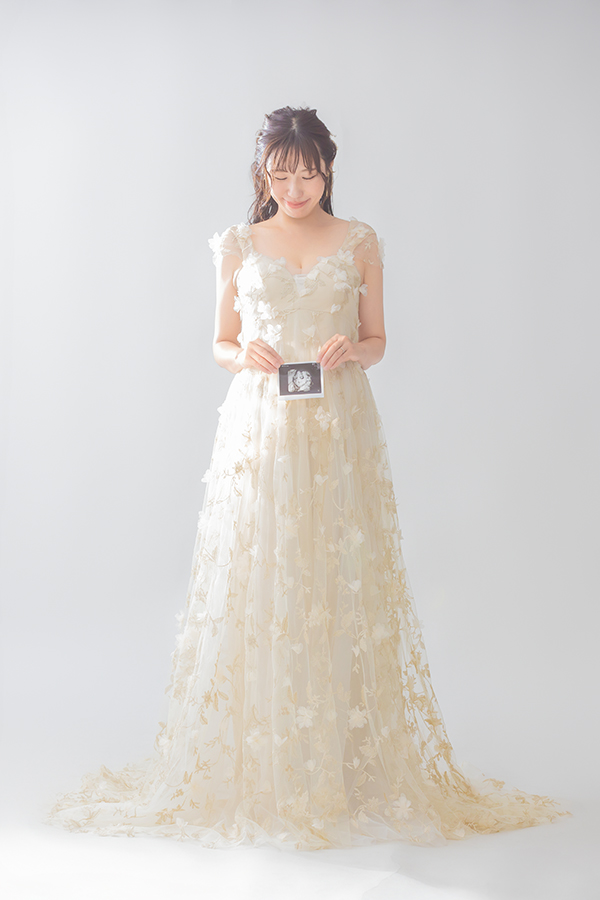 アイボリーの刺繍ドレス、エコー写真を手に