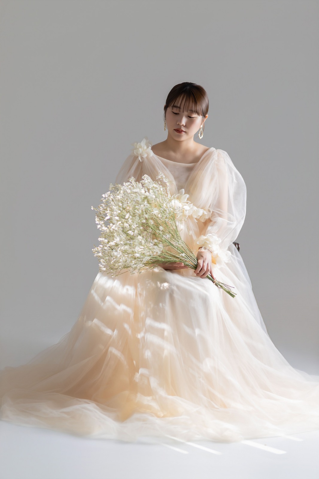 アイボリーのドレス、花束を手に