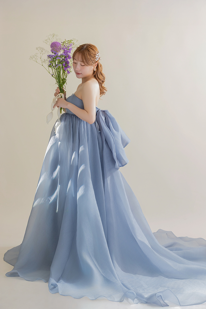 ブルーのボリュームドレス、花束を手に