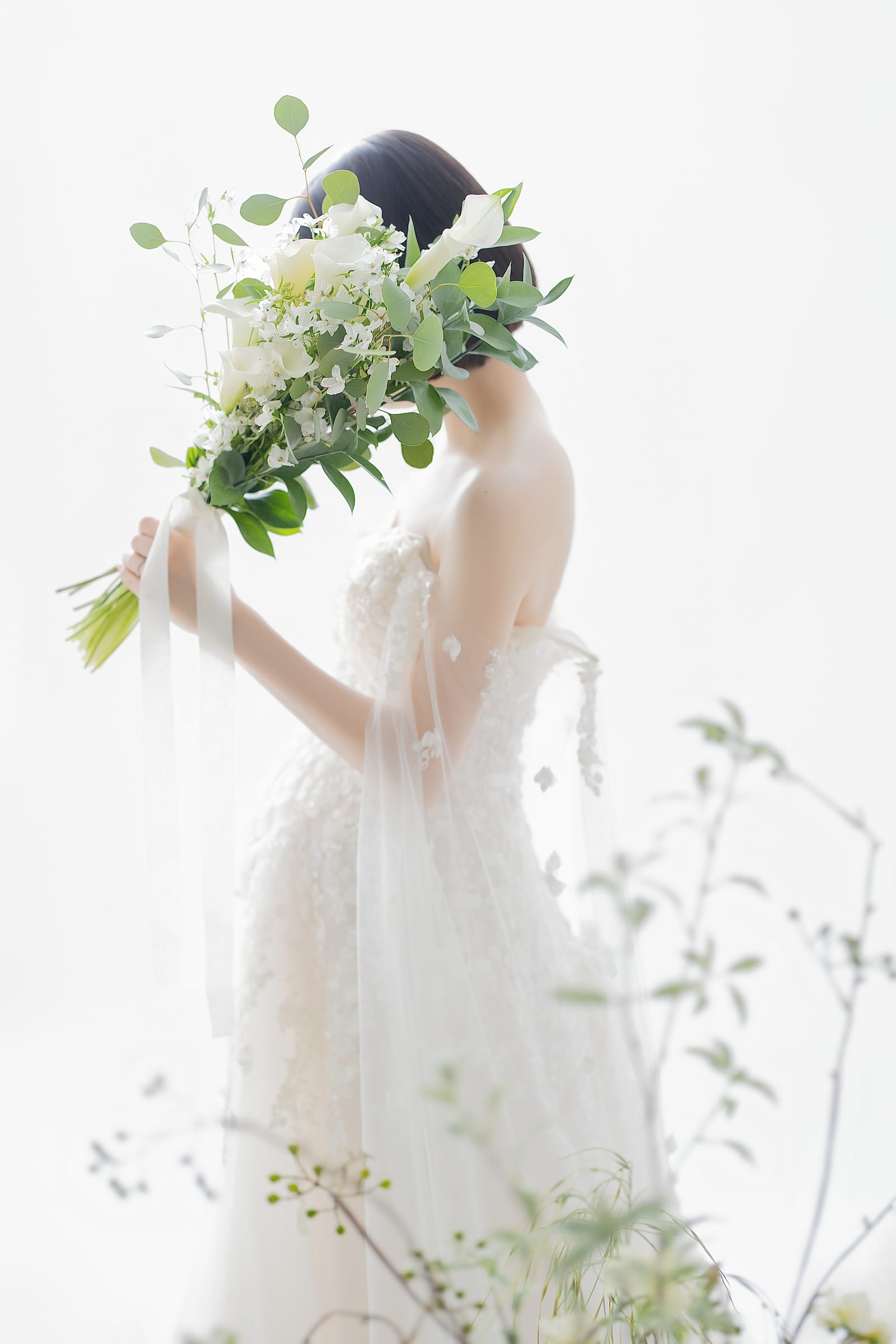 白いドレスで大きなブーケを顔の高さに掲げる妊婦