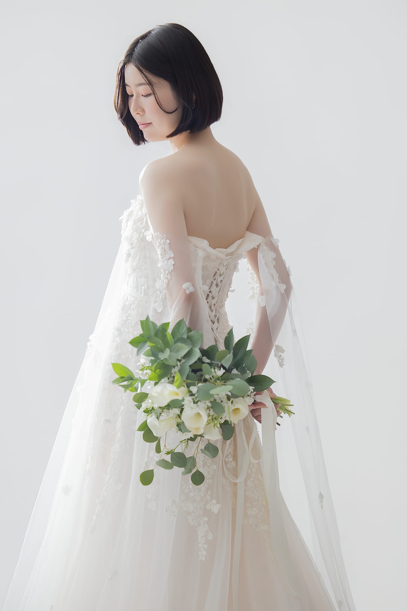 白いレースのウェディングドレスでブーケを抱える妊婦