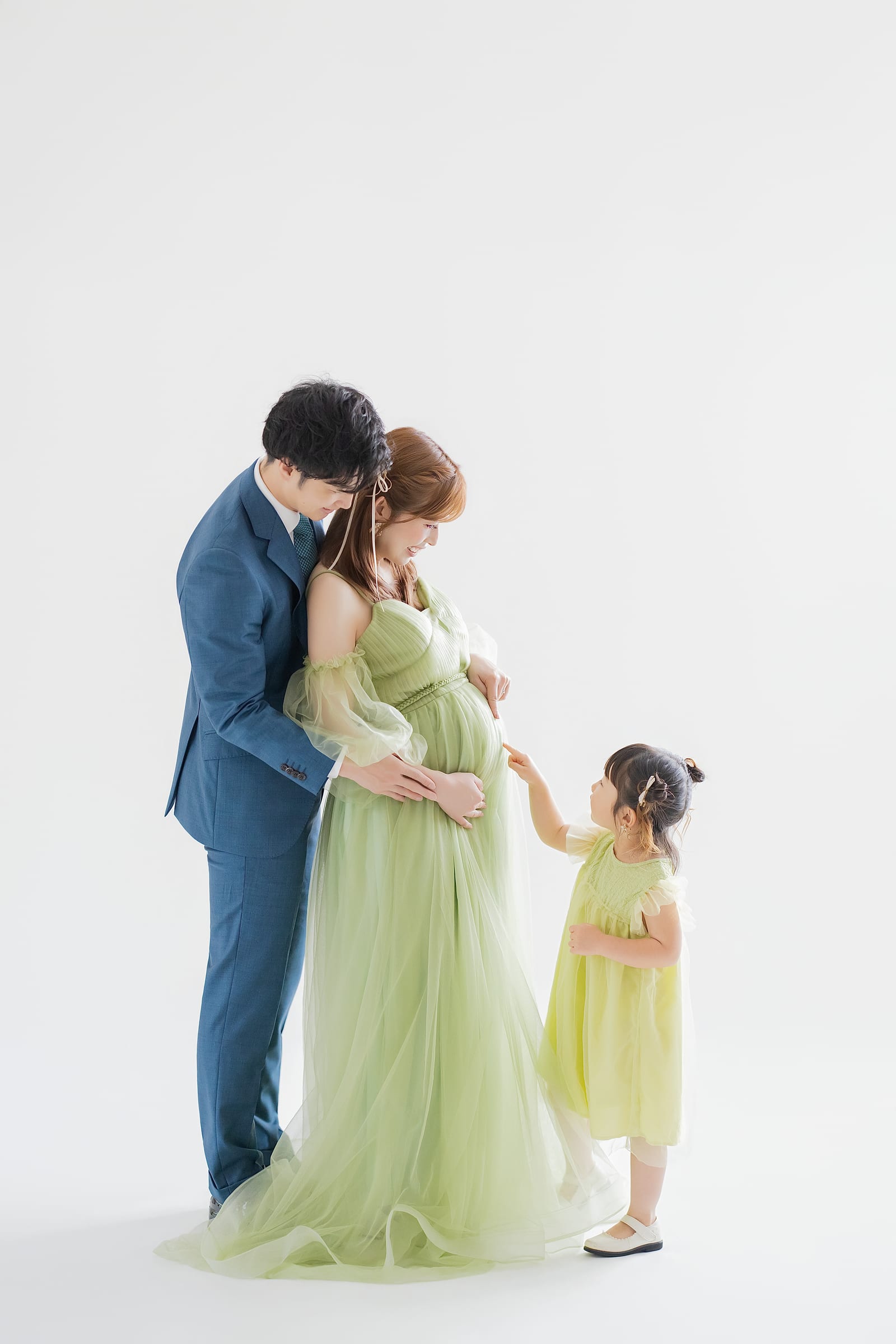 グリーンのドレスをまとった母と、手を伸ばす上の子とご主人