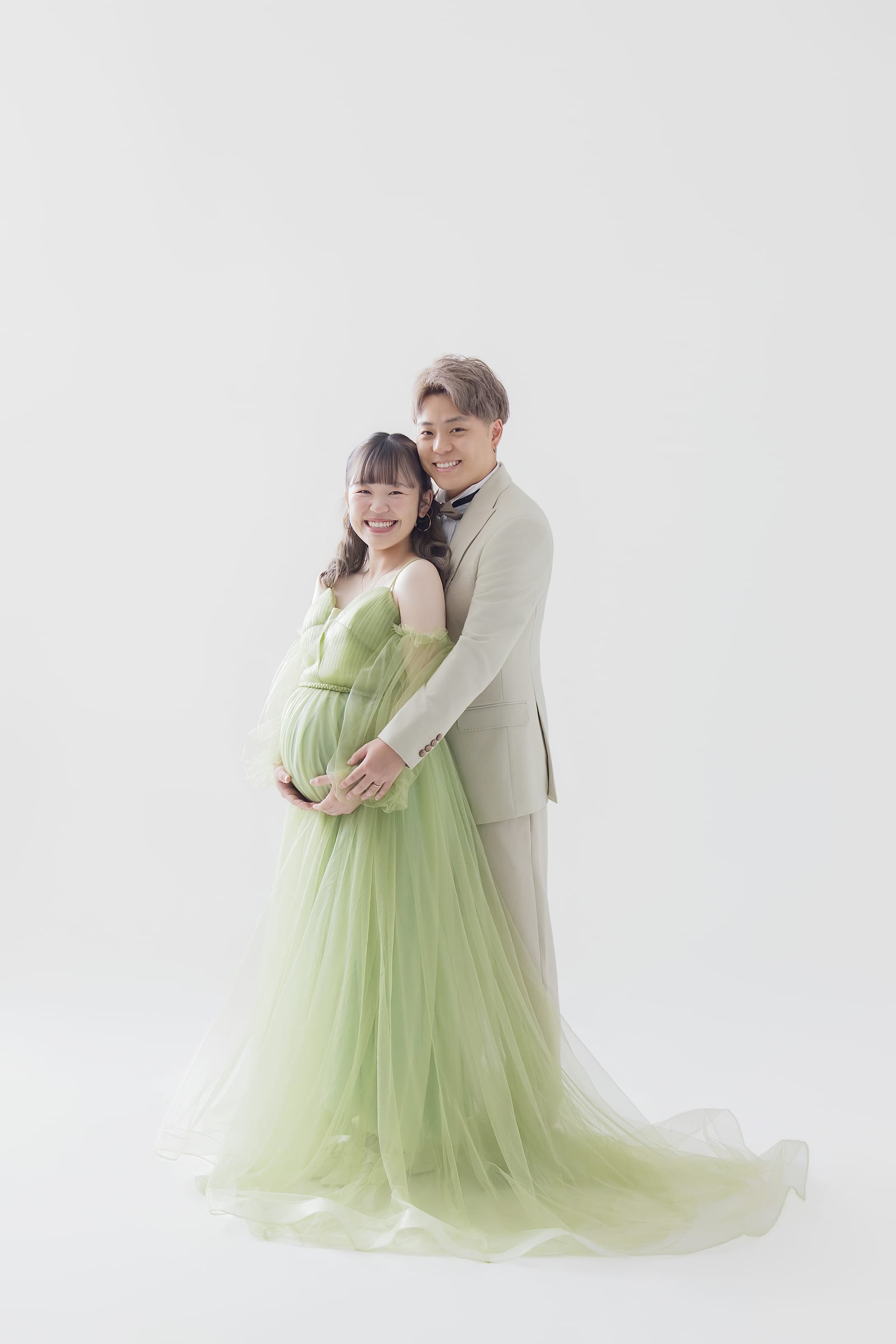 グリーンのドレスとベージュのスーツで寄り添うご夫婦
